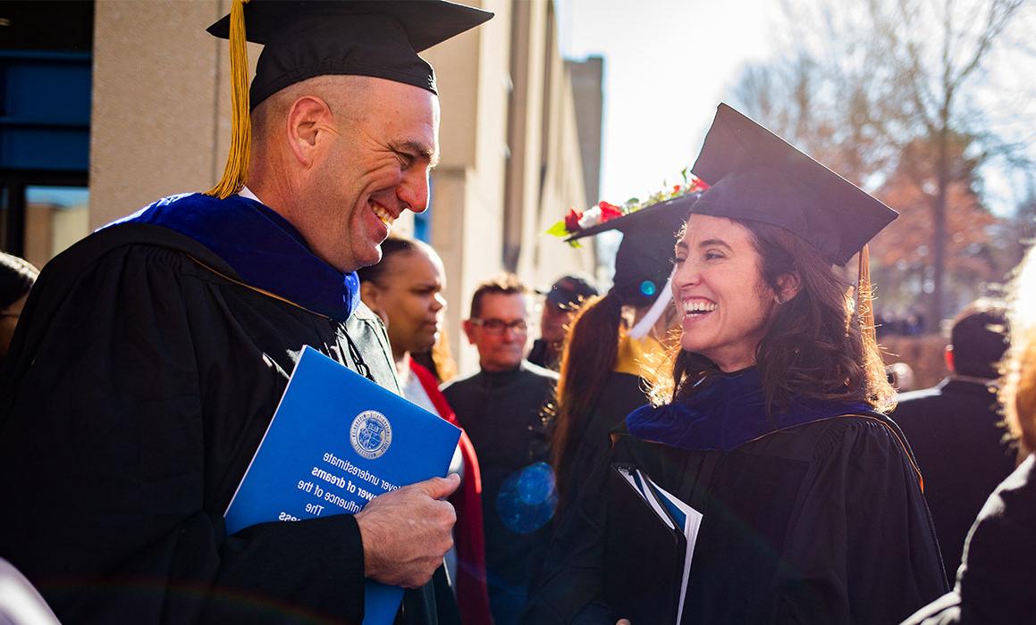 戴毕业帽和毕业服的白人女性向戴毕业帽和毕业服的白人男性微笑
